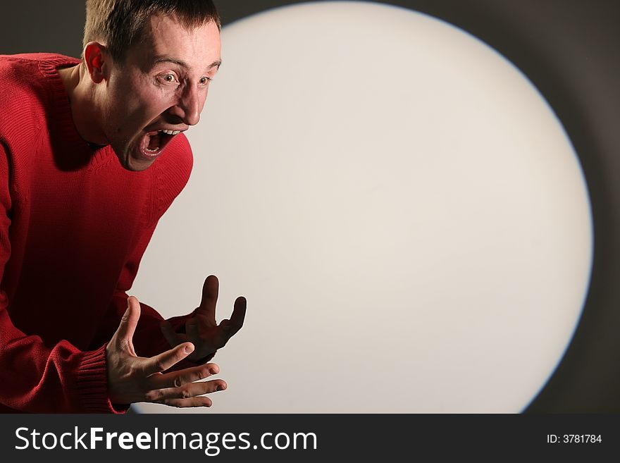 Young man in red pullover screaming and gesticulating - with a white circle in the background. Young man in red pullover screaming and gesticulating - with a white circle in the background.