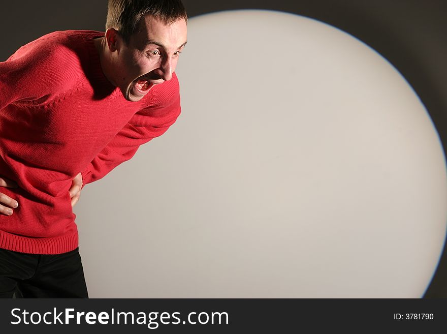 Young man in red pullover screaming and gesticulating - with a white circle in the background. Young man in red pullover screaming and gesticulating - with a white circle in the background.