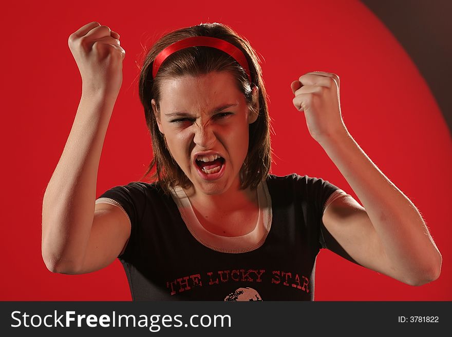 Angry girl in a Tshirt with clenched fists on red background and making gesture. Angry girl in a Tshirt with clenched fists on red background and making gesture.