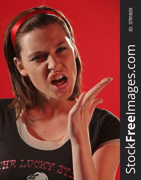 Young angry woman in a brown Tshirt on a red background making gesture. Young angry woman in a brown Tshirt on a red background making gesture.