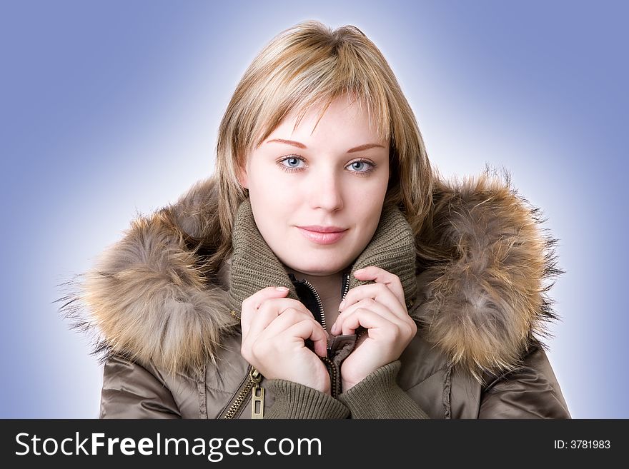 Young girl in a jacket with a fur collar on a light blue background