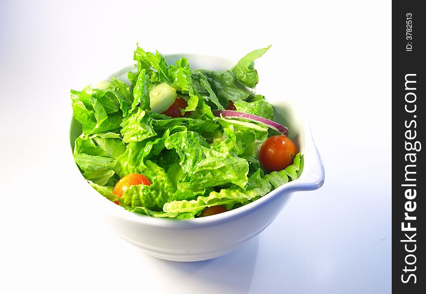 Green Leafy salad in a white bowl on white background