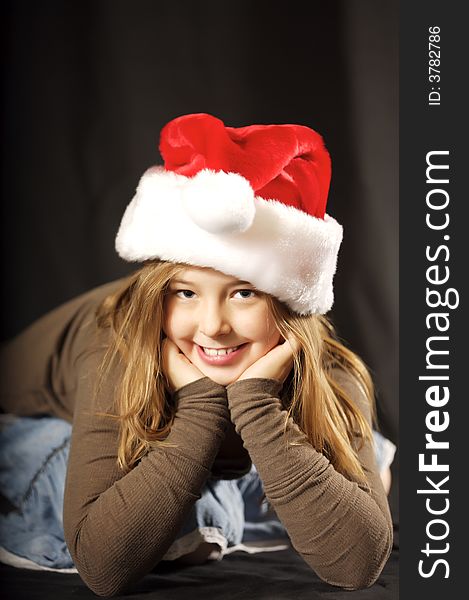 Cute young girl wearing a santa hat with a big smile on her face. Cute young girl wearing a santa hat with a big smile on her face