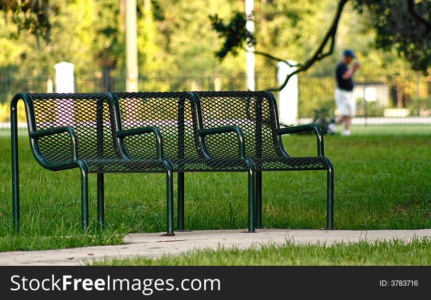A shaded park bench with man in background