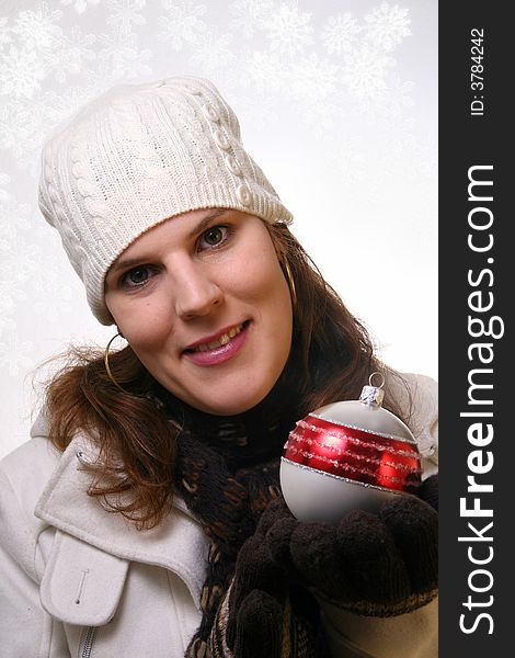 A young woman is holding christmas decoration. She is happy with winter gear on. Isolated over white with space for text. A young woman is holding christmas decoration. She is happy with winter gear on. Isolated over white with space for text.