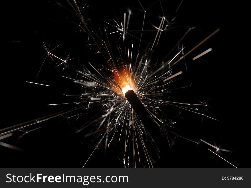 Burning sparkler against black background