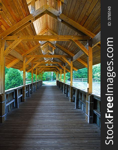 Looking down the length of a wooden covered bridge for pedestrian use. Looking down the length of a wooden covered bridge for pedestrian use.