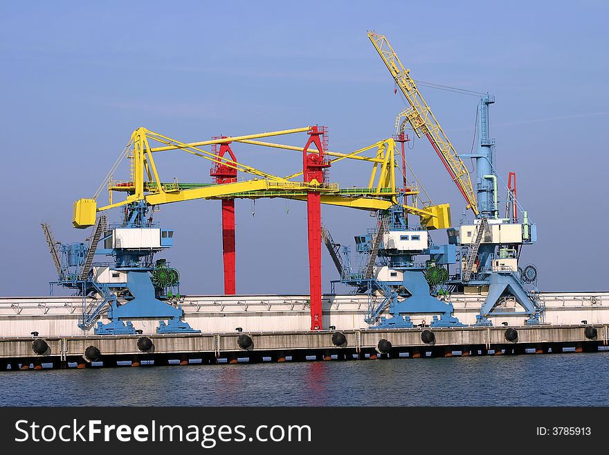 Many docking cranes on blue sky background