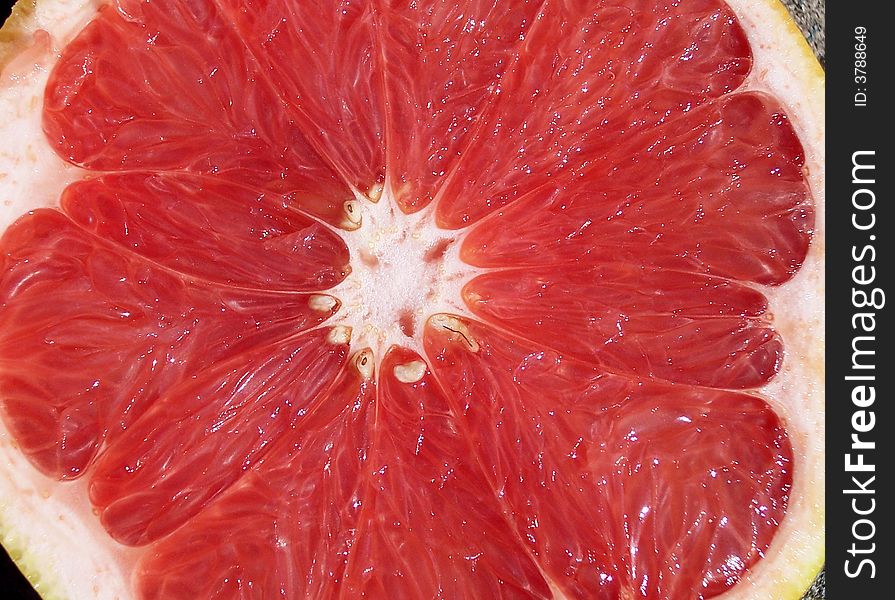 A cut red grapefruit open faced, view from above.