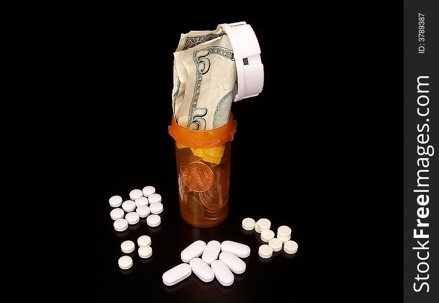 Prescription pills laying around a bottle filled with coins and bills on a black background. Prescription pills laying around a bottle filled with coins and bills on a black background.