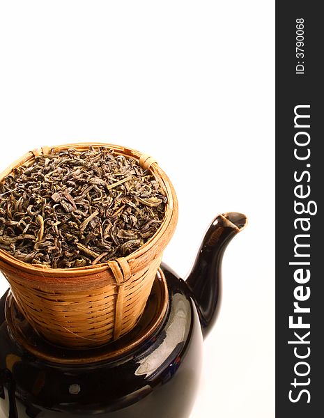 Green tea leaves in bamboo tea strainer on a tea pot. Green tea leaves in bamboo tea strainer on a tea pot.