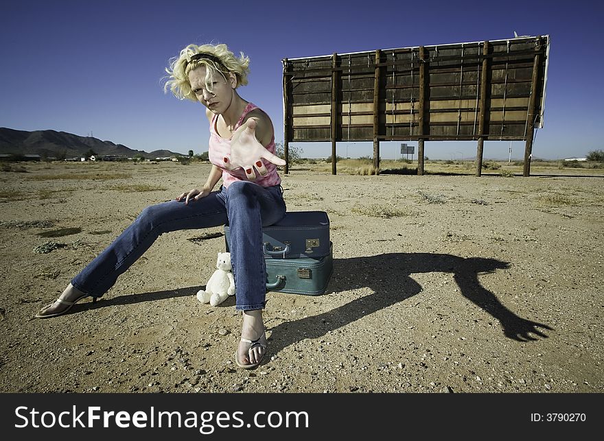 Woman sitting on suitcases in front of an old billboard reaching to the camera. Woman sitting on suitcases in front of an old billboard reaching to the camera