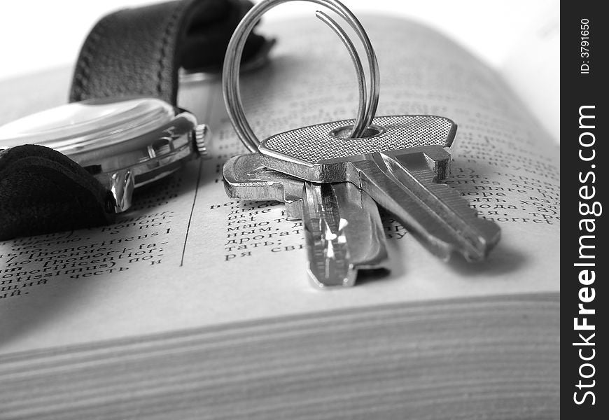 Bunch of keys with watch on page of open book. Bunch of keys with watch on page of open book