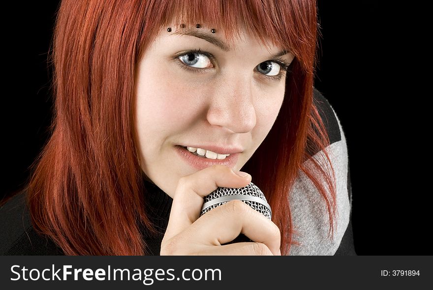 Cute smiling redhead girl singing on microphone.

Studio shot.