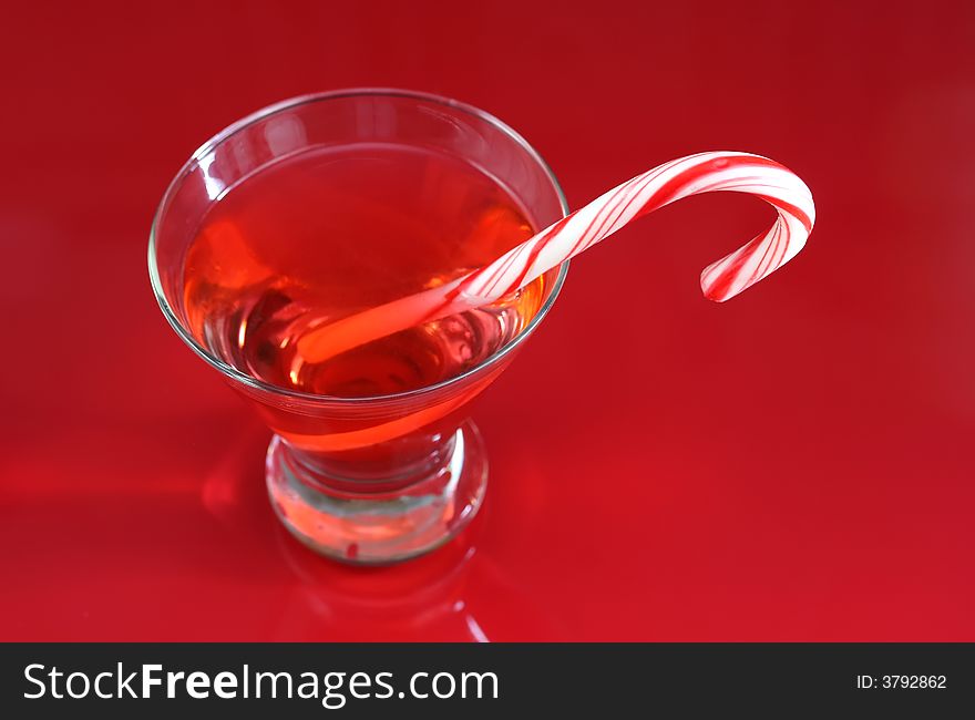 A christmas martini with a candy cane on a red background. A christmas martini with a candy cane on a red background