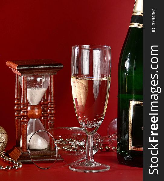 New yearâ€˜s still life with sandglass and champagne on the red. New yearâ€˜s still life with sandglass and champagne on the red