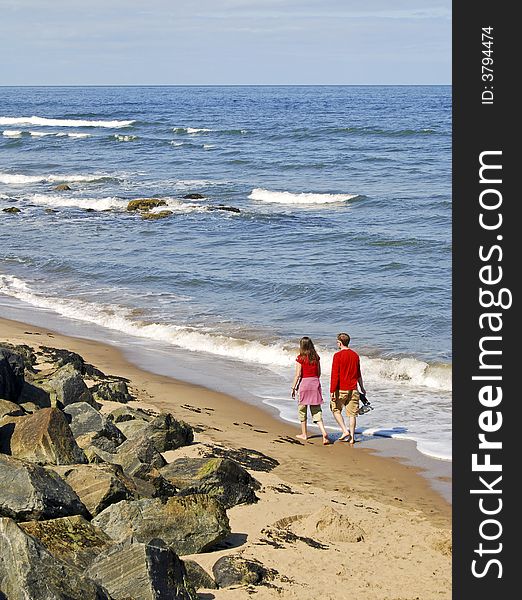 Young couple walk on sandy beach on sunny day. Young couple walk on sandy beach on sunny day