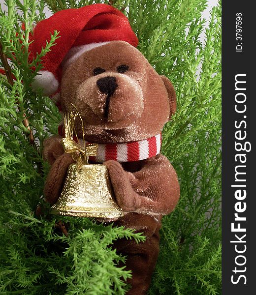 Christmas teddy-bear handing small golden bell