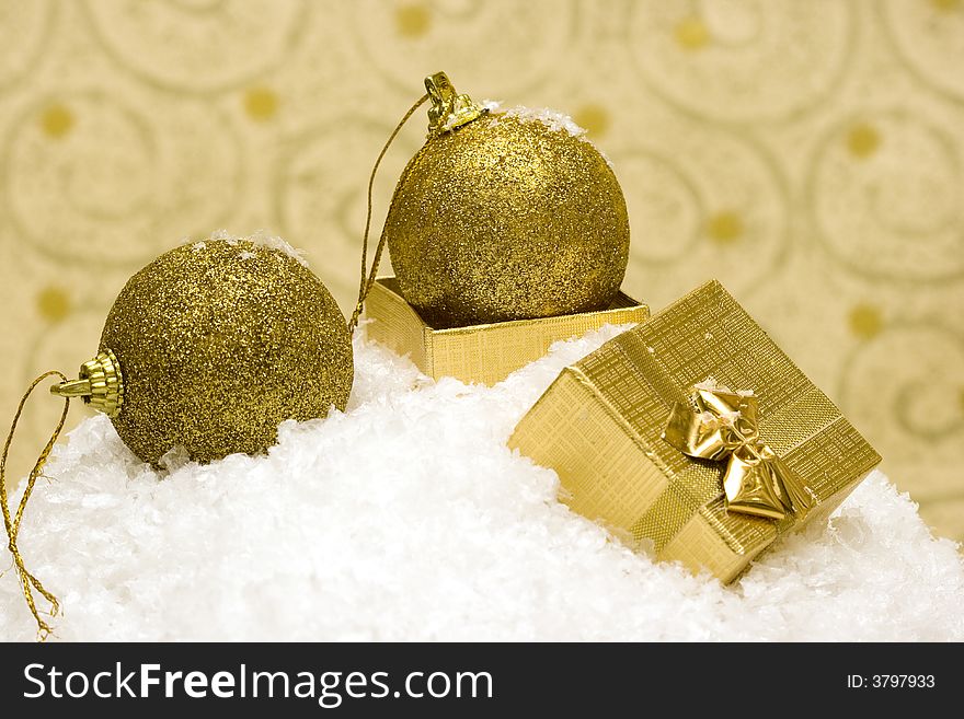 Golden Christmas balls and gift on snow