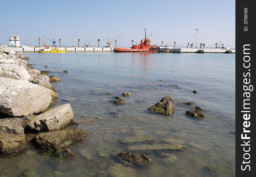 Tranquila harbour image reflecting the shoreline and the pier with the pilot boat moored.