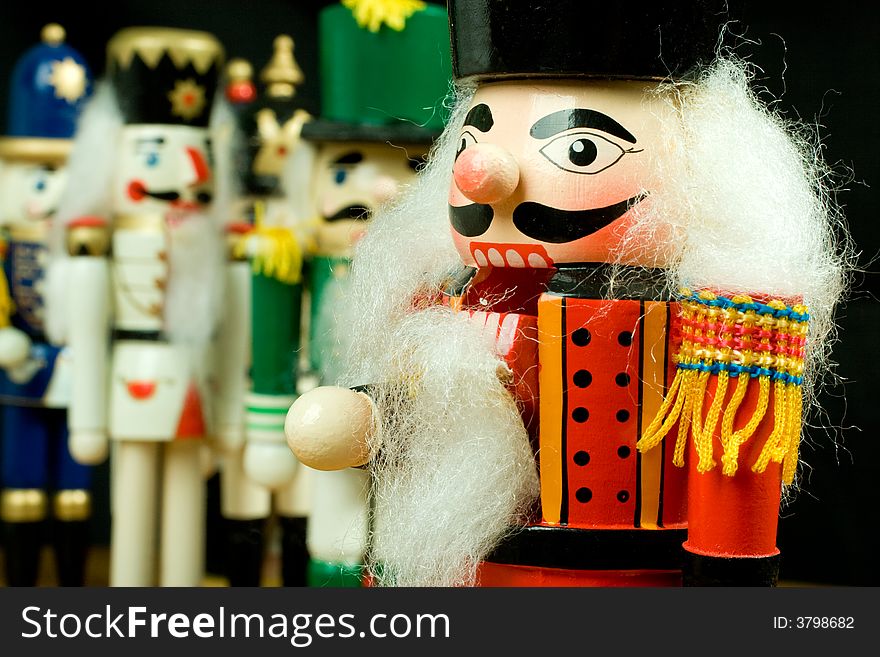 Closeup of a wood toy soldier nutcracker with the platoon looking on in the background. Closeup of a wood toy soldier nutcracker with the platoon looking on in the background