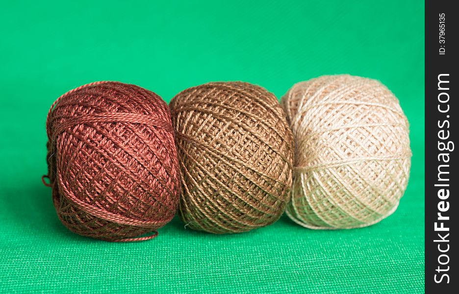 Some balls of a multi-colored yarn on a green background