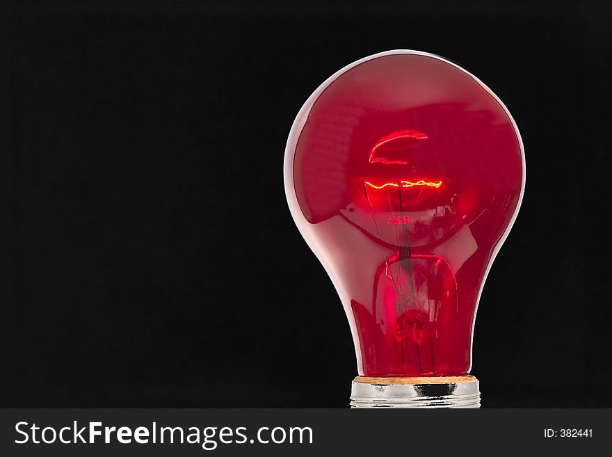 Red light bulb in front of a black background. Red light bulb in front of a black background