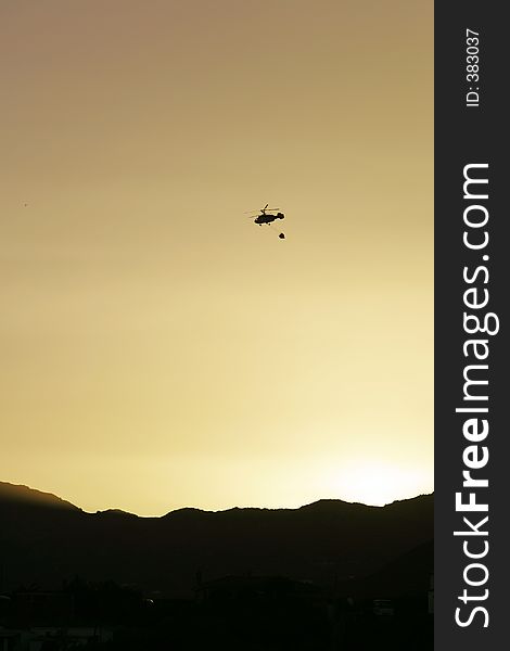 Firefighter helicopter flying over mountains to fire at sunset. Firefighter helicopter flying over mountains to fire at sunset