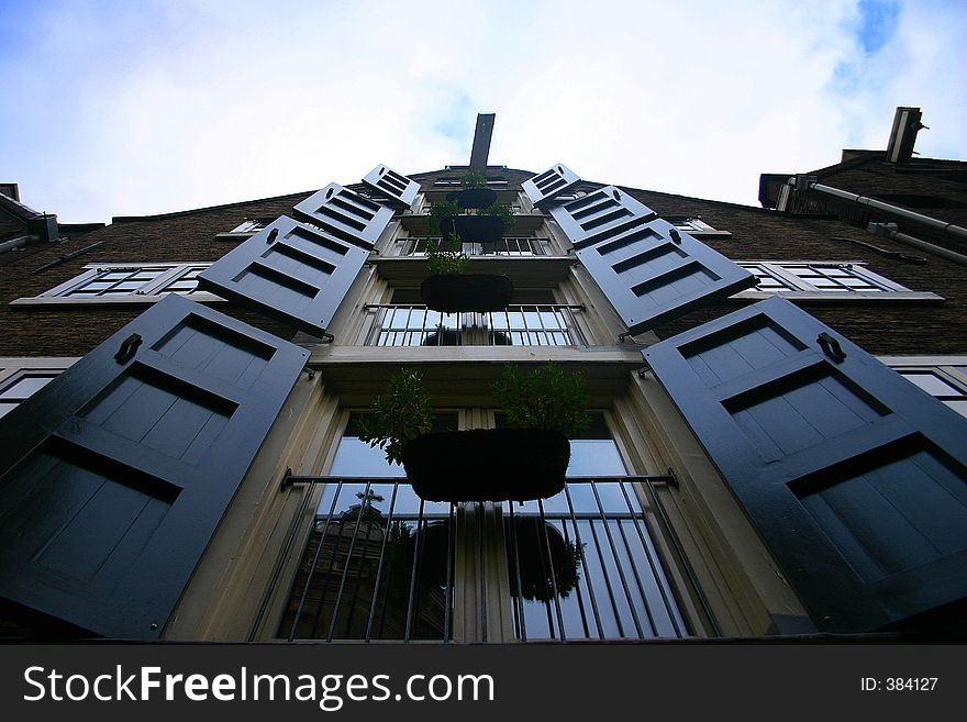 The facade of an old home in Amsterdam, green shutters on the windows. The facade of an old home in Amsterdam, green shutters on the windows.