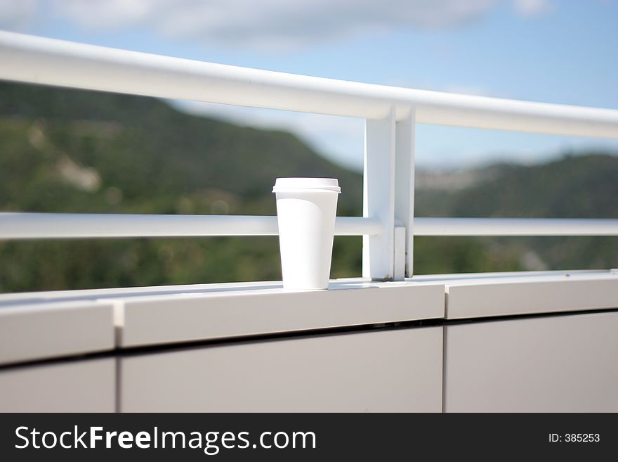 Cup on the wall, coffee cup, white, blur background, blue sky, water. Cup on the wall, coffee cup, white, blur background, blue sky, water