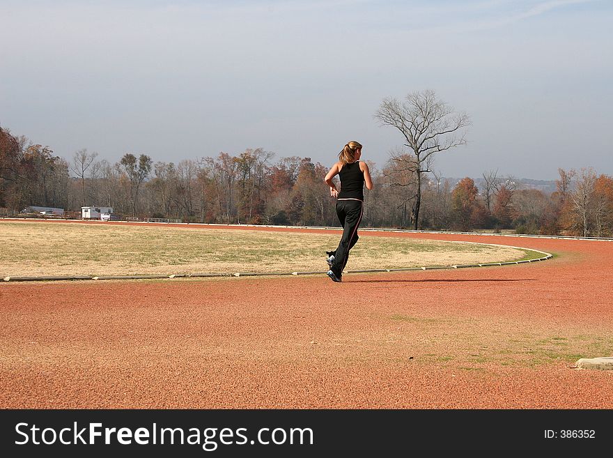 Young woman running outdoors at the track. Young woman running outdoors at the track.