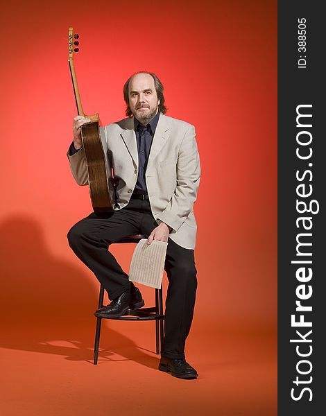 Middle aged man-musician leaning on a chair with his guitar and musical notes in his hands on a red background. Last of the series! :)