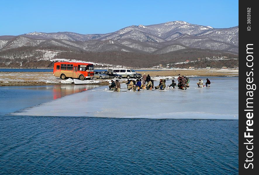 A group of the fishers is on ice cake. Early spring. Russian Far East, Primorsky Region, Japanese sea, Sokolovskaya bay. A group of the fishers is on ice cake. Early spring. Russian Far East, Primorsky Region, Japanese sea, Sokolovskaya bay.