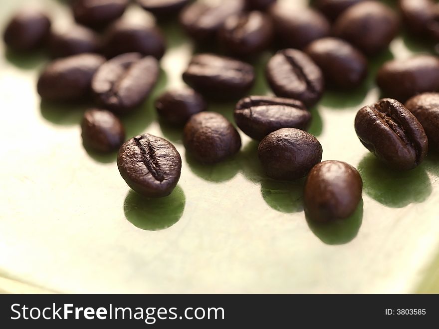 A close up image of coffee beans on agreen background. A close up image of coffee beans on agreen background