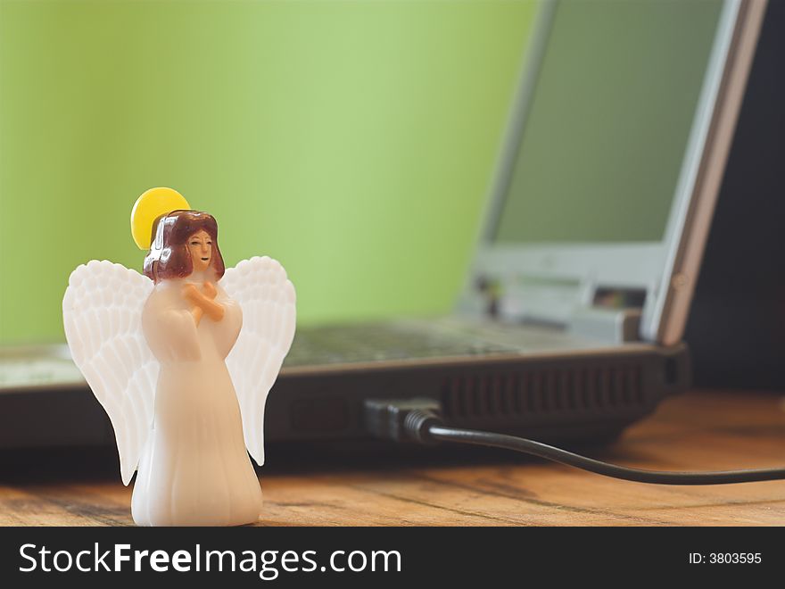 A toy angel in front of a notebook symbolizing christmas present or help with computer problems. A toy angel in front of a notebook symbolizing christmas present or help with computer problems