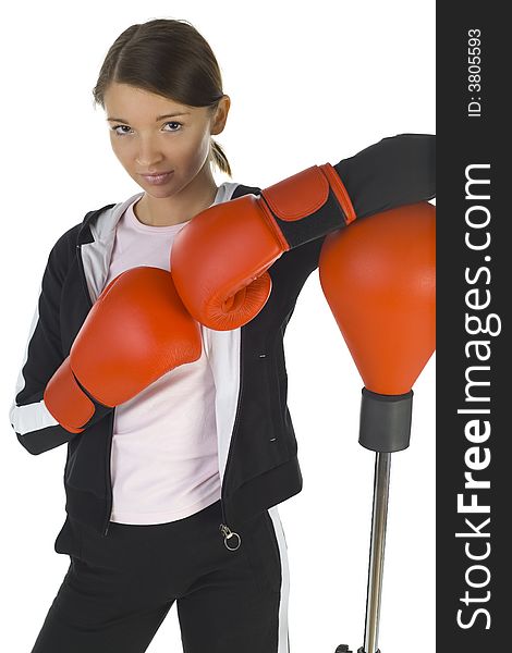 Young beauty with boxing gloves. Standing next to punch bag. Looking at camera. White background, front view. Young beauty with boxing gloves. Standing next to punch bag. Looking at camera. White background, front view