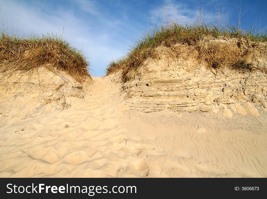 Looking up at a sand dune and the blue sky