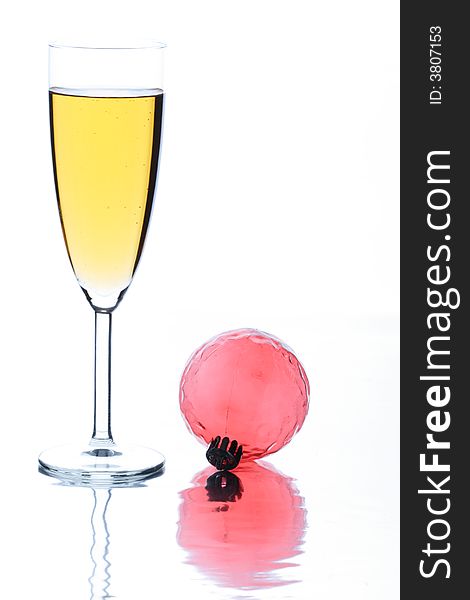Glass with champagne on a white background and a Christmas ornament. Glass with champagne on a white background and a Christmas ornament