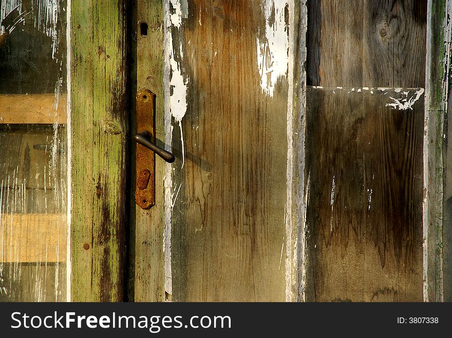 Old wooden door with rusted handle and interesting texture.