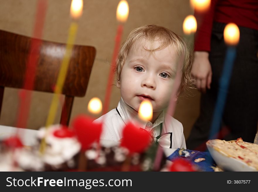 The boy look at cake with candles. The boy look at cake with candles