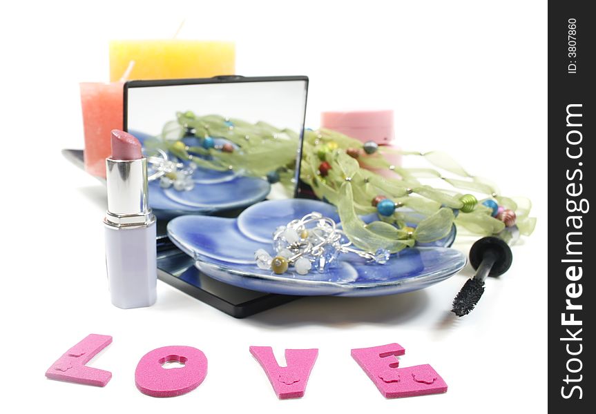 Word love, Jewelry and make up (lipstick, blush, eye care) and candles isolated over white