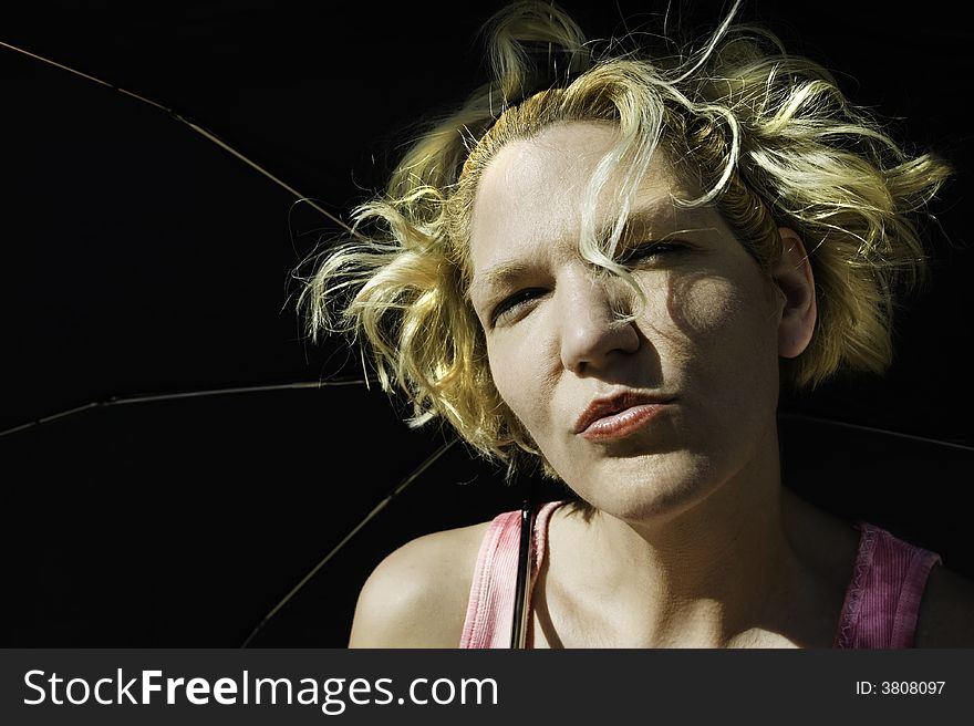 Blonde woman with crazy hair under a black umbrella. Blonde woman with crazy hair under a black umbrella