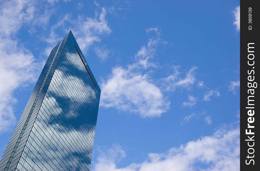 The John Hancock tower in Boston reflecting clouds on a sunny day.