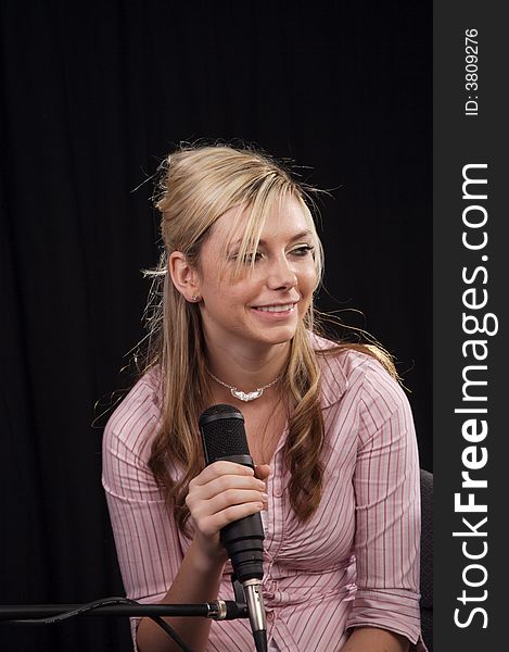 Beautiful young woman singing into a microphone. Beautiful young woman singing into a microphone