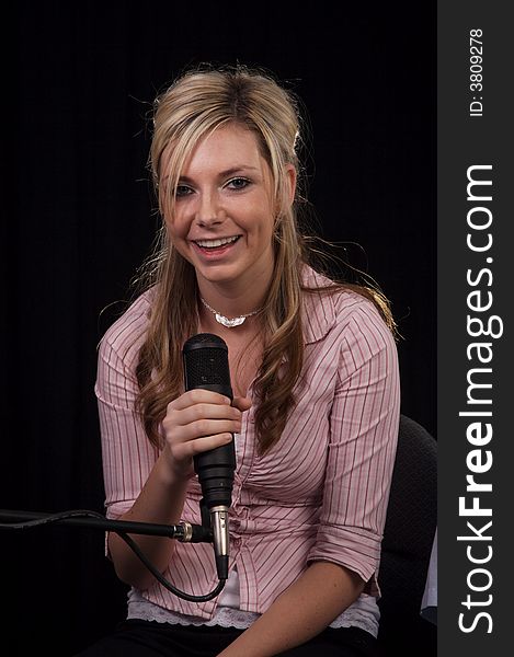 Beautiful young woman singing into a microphone. Beautiful young woman singing into a microphone