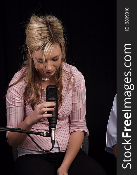 Beautiful young woman singing into a microphone. Beautiful young woman singing into a microphone