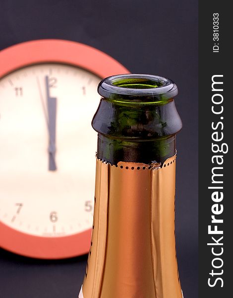 A clock ticking away the final seconds behind an uncorked bottle of champagne, shallow DOF, focus is on the bottle. A clock ticking away the final seconds behind an uncorked bottle of champagne, shallow DOF, focus is on the bottle
