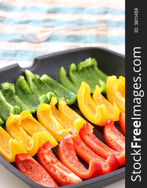 Colorful rows of green, yellow and red capsicum strips prepared for cooking on a pan. Colorful rows of green, yellow and red capsicum strips prepared for cooking on a pan