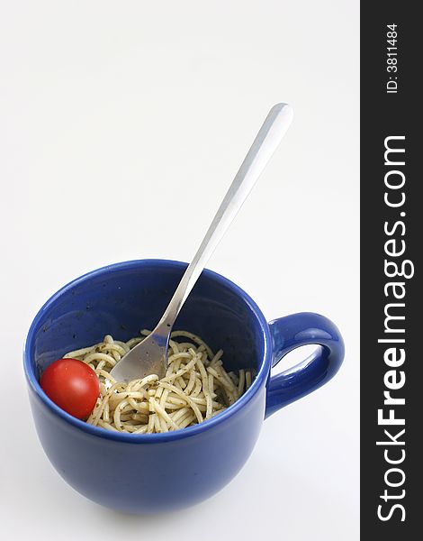 Pasta olio with a cherry tomato in a large blue ceramic cup