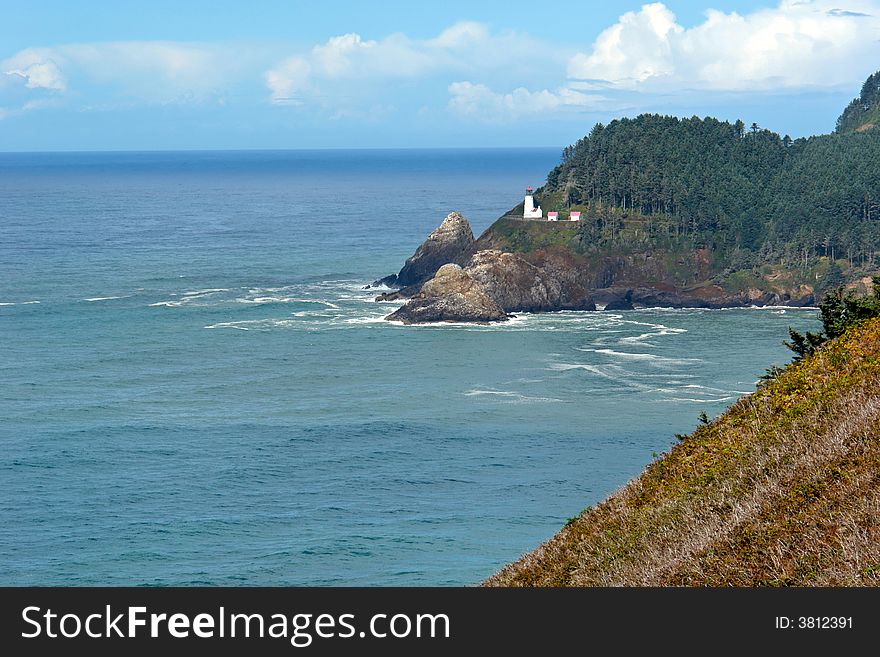 Rich beautiful scenic view of the oregon coast with waves crashing and lighthouse off in the distance. Rich beautiful scenic view of the oregon coast with waves crashing and lighthouse off in the distance